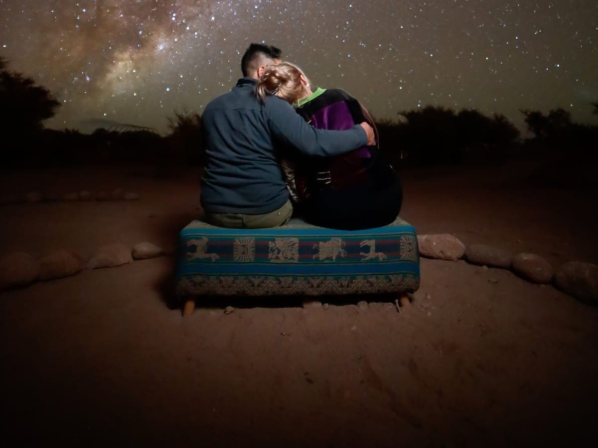 A couple embracing on an observatory bench beneath the Milky Way